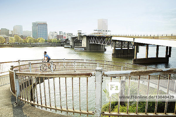 Fahrrad fahrender männlicher Athlet auf einer Brücke in der Stadt