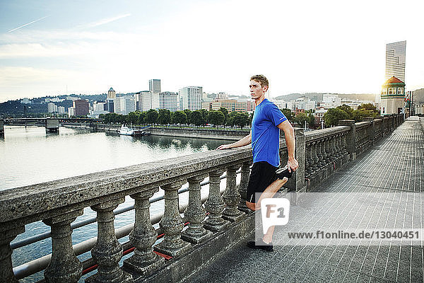 Sporty man exercising on bridge in city