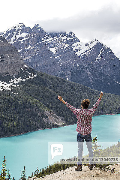 High angle view of hiker with arms raised standing against Peyto Lake and mountains