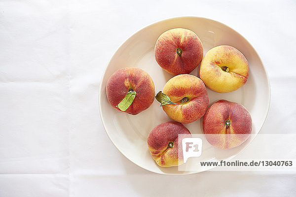 Draufsicht auf Pfirsiche in Tellerform über weißem Hintergrund