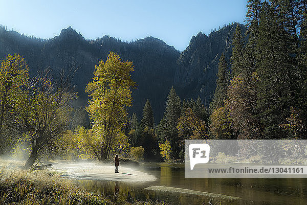 Wanderin im Yosemite-Nationalpark an Fluss und Bergen stehend
