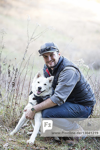 Porträt eines Mannes mit Hund auf dem Feld kauernd