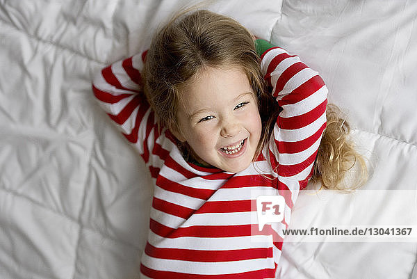 Kopfporträt eines lächelnden Mädchens  das an Weihnachten auf dem Bett liegt