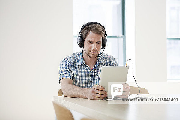 Businessman listening music through tablet computer in creative office