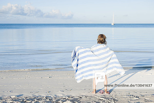 Rückansicht eines Mädchens mit Handtuch am Strand