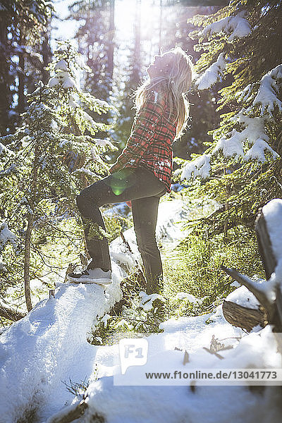 Seitenansicht einer fröhlichen Frau im Wald im Winter