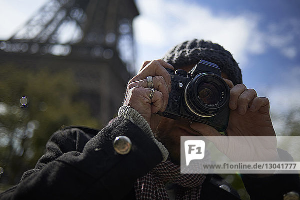 Männlicher Tourist fotografiert mit DSLR-Kamera vor dem Eiffelturm