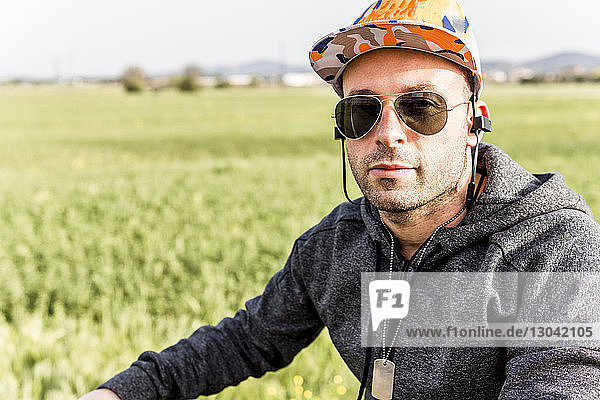 Portrait of man wearing sunglasses by farm against sky