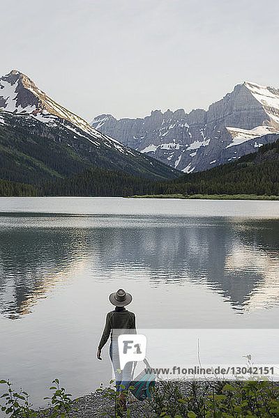 Rückansicht einer Wanderin  die am Swiftcurrent Lake stehend auf den Mt. Grinnell blickt