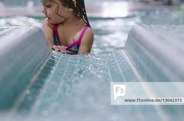 Girl standing against water slide in swimming pool