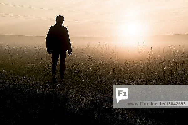 Silhouettenmann steht bei Sonnenuntergang auf dem Feld