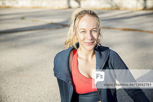 Portrait of smiling female athlete relaxing on footpath