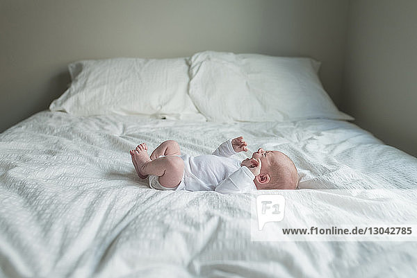 Seitenansicht eines Neugeborenen  der weint  während er zu Hause im Bett liegt