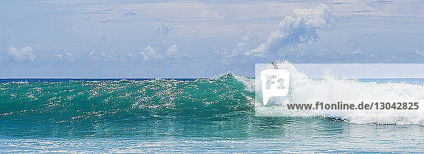 Panoramablick Surfer surfen auf riesigen Meereswellen gegen den Himmel