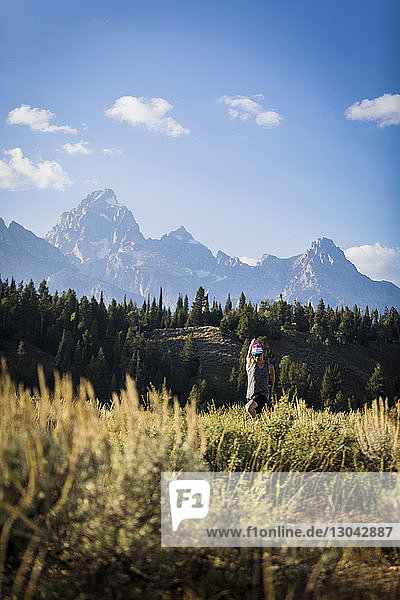 Man stretching arms while practicing yoga on field against mountains at Bridger-Teton National Forest