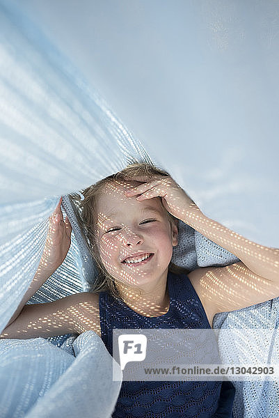 Cheerful girl playing under blanket