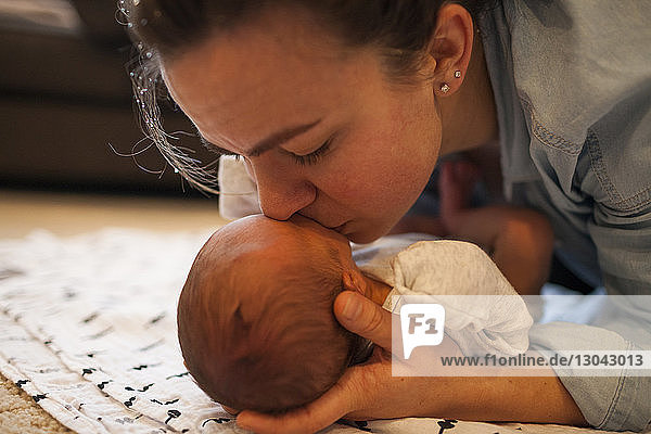 Nahaufnahme einer Mutter  die ein Neugeborenes zu Hause küsst