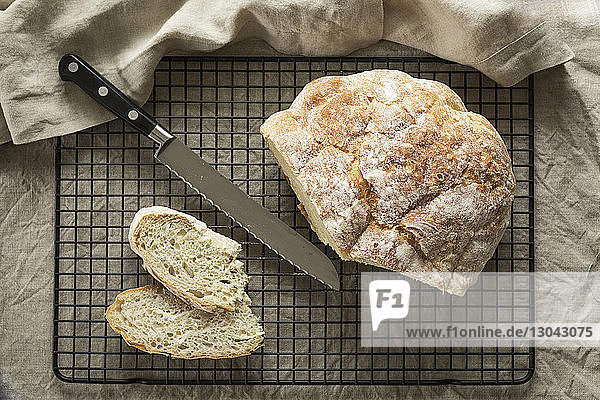 Draufsicht auf Brot mit Küchenmesser auf Kühlgestell