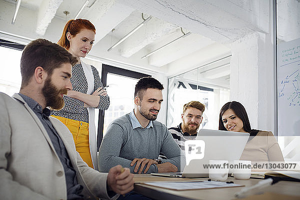 Business people using laptop in board room