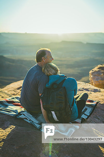 Rear view of romantic couple sitting on mountain at Canyonlands National Park