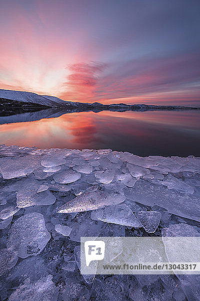 Szenische Ansicht des Sees vor dramatischem Himmel mit Eis im Vordergrund