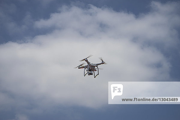 Tiefwinkelansicht einer Drohne  die gegen bewölkten Himmel fliegt