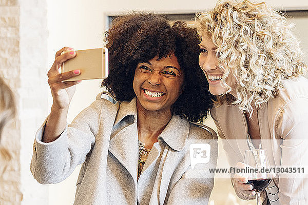 Fröhliche Geschäftsfrauen  die sich im Hotel mit einem Smartphone selbstständig machen