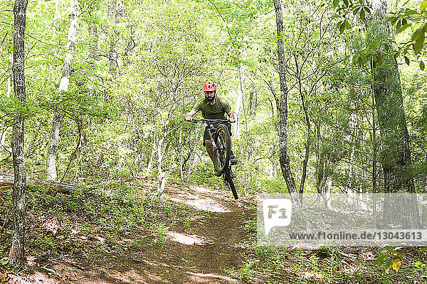 Sporty hiker mountain biking in forest