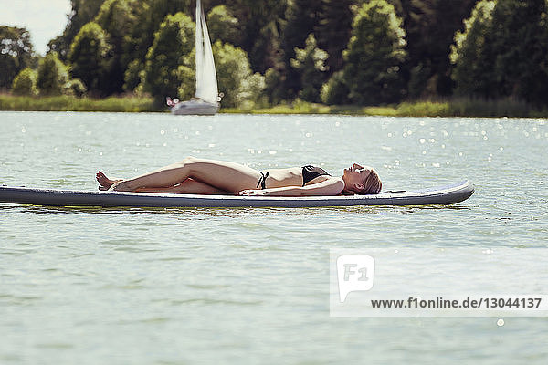Sinnliche Frau entspannt sich auf einem Paddelbrett im See