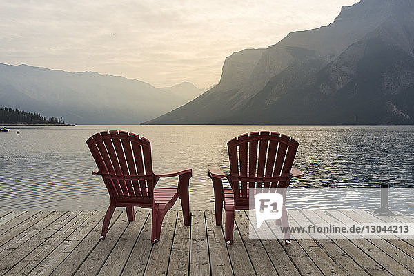 Stühle auf dem Steg über dem Minnewanka-See gegen die Berge im Banff-Nationalpark