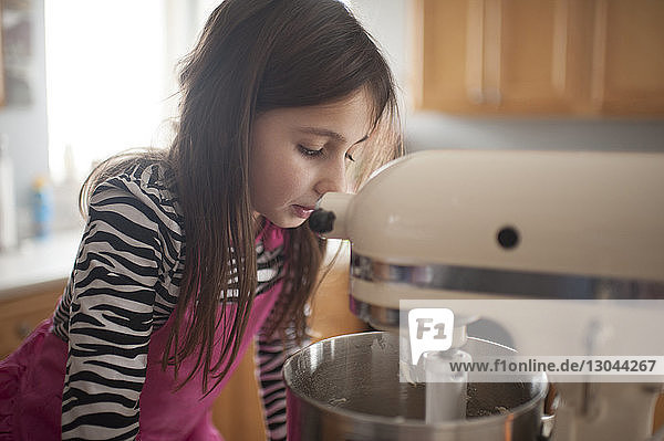 Mädchen betrachtet Mixer in der Küche zu Hause