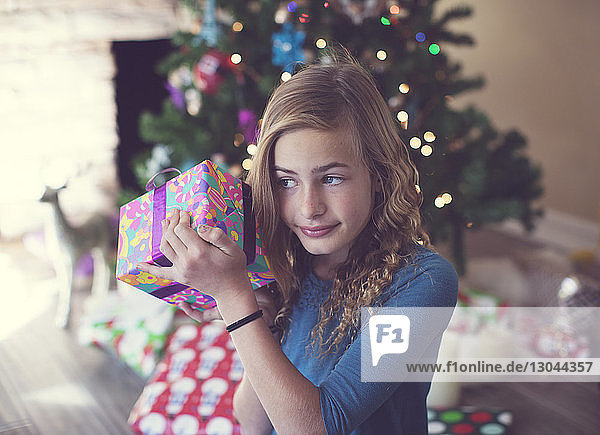 Girl holding Christmas present while sitting at home