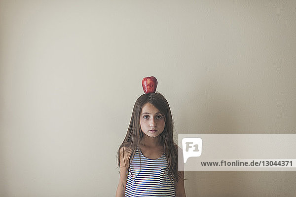 Bildnis eines Mädchens  das einen Apfel auf dem Kopf trägt  während es zu Hause an der Wand steht