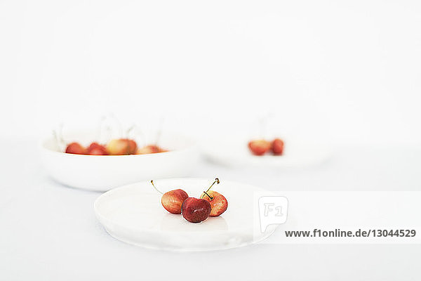 Hochwinkelansicht von Kirschen in Tellern auf weißem Hintergrund