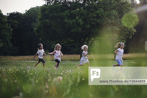 Friends running on grassy field at park