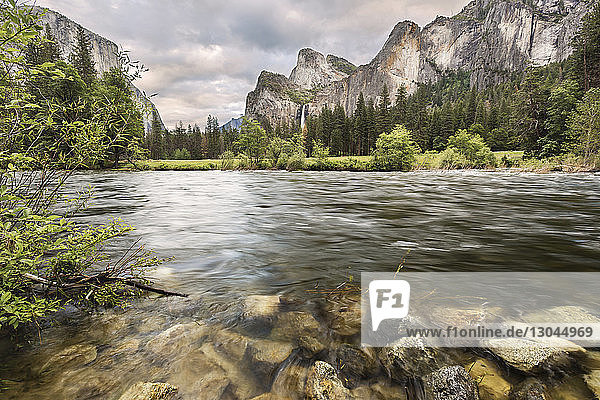 Scenic view of river by mountains against cloudy sky at Yosemite National Park