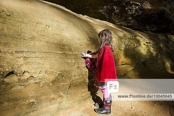 Seitenansicht eines Mädchens  das eine Felsformation im Wald betrachtet
