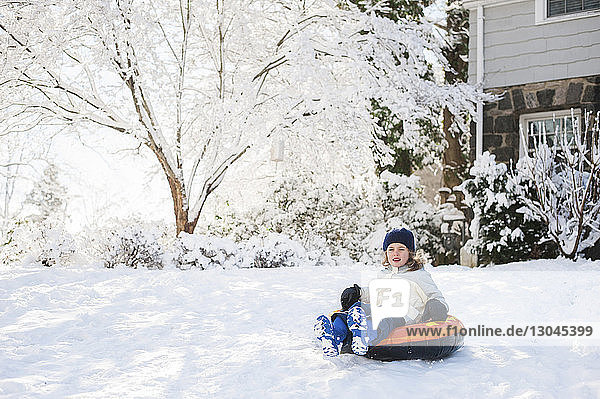 Happy girl sitting on inflatable ring in backyard during winter