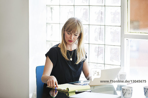 Businesswoman using laptop on table in creative office