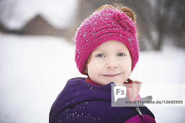 Porträt eines lächelnden Mädchens  das bei Schneefall im Freien steht
