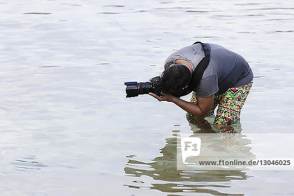 Mann fotografiert im Meer stehend