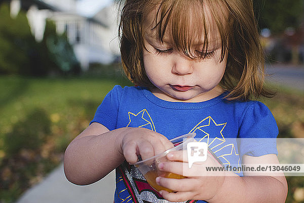 Close-up of girl picking fruit from glass while standing in park