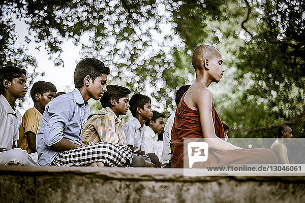 Mönch sitzt mit Kindern beim Meditieren