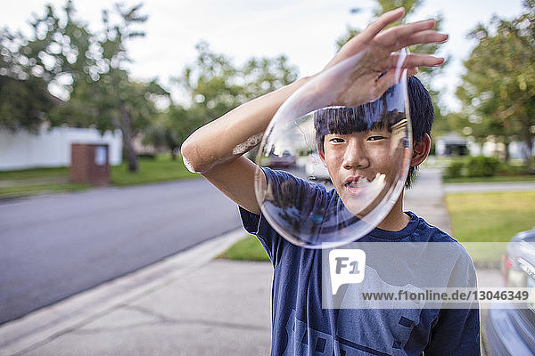 Porträt eines auf einem Fußweg stehenden Teenagers mit Blase