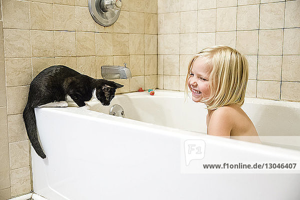 Cheerful girl with cat in bathtub