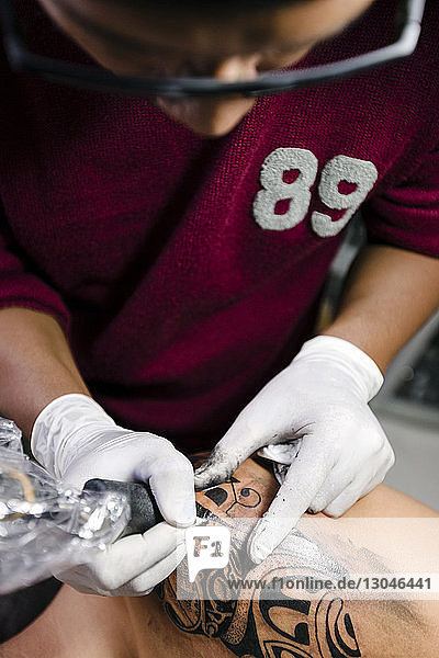 High angle view of tattoo artist tattooing man's shoulder
