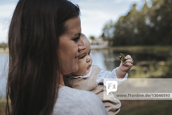 Side view of mother with son standing against lake