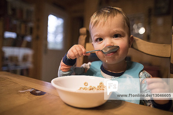 Portrait of cute baby boy eating breakfast while sitting at home