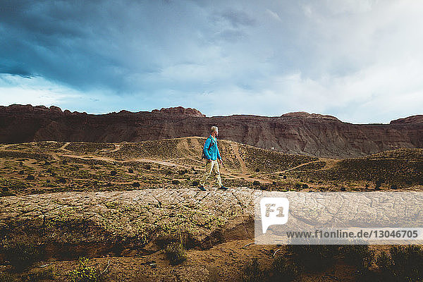 Seitenansicht eines männlichen Wanderers  der im Canyonlands-Nationalpark gegen die Berge läuft