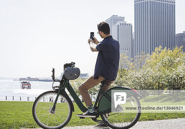 Side view man taking selfie while sitting on bicycle in city